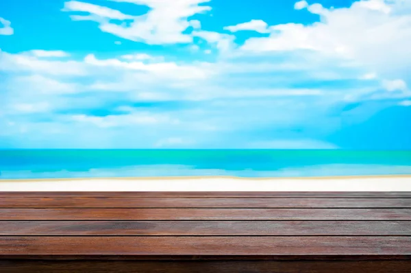 Holz Tischplatte auf verschwommenem weißen Sandstrand und blauem Himmel Hintergrund — Stockfoto