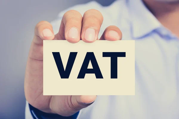 VAT letters (or Value Added Tax) on business card shown by a man — Stock Photo, Image