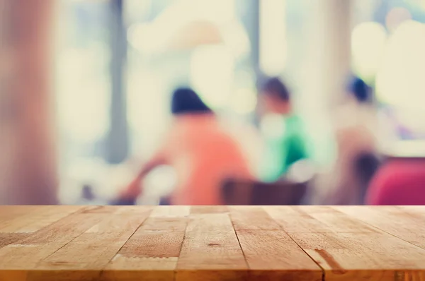 Mesa de madera sobre fondo borroso de la gente en la cafetería —  Fotos de Stock