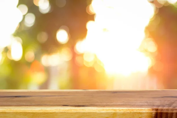 Mesa de madera sobre fondo borroso bokeh de luz solar que brilla a través de los árboles —  Fotos de Stock