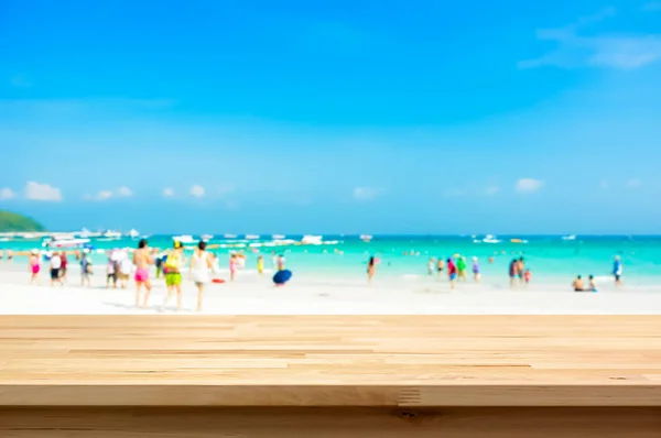 Piano in legno su sfondo spiaggia sfocata con persone in vestiti colorati — Foto Stock