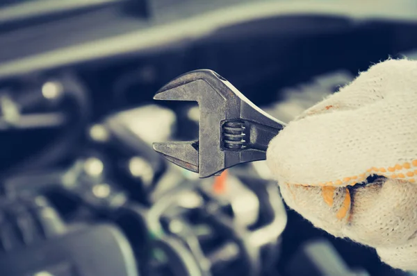 Hand holding wrench on blur car engine background — Stock Photo, Image