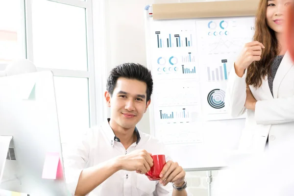 Bello casual asiatico uomo d'affari sorridente mentre tiene la tazza di caffè in ufficio — Foto Stock