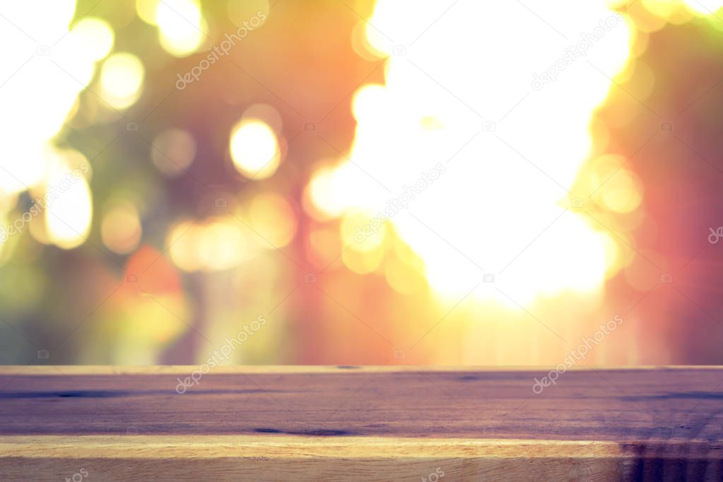 Wood table top on blur bokeh background of sunlight shining through the trees