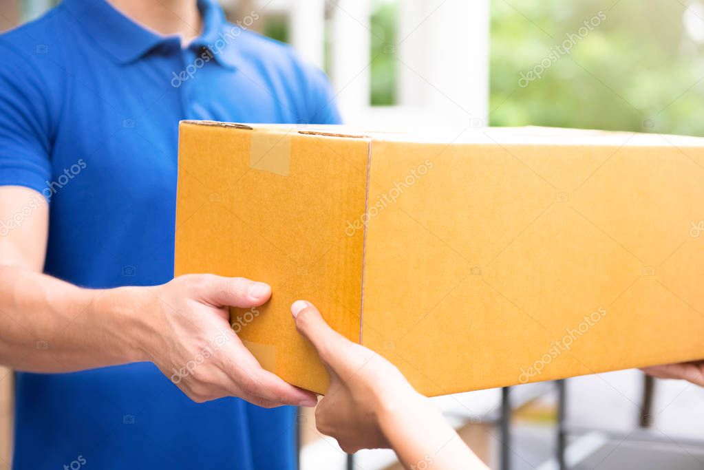 Delivery man in blue uniform handing parcel boxes to recipient
