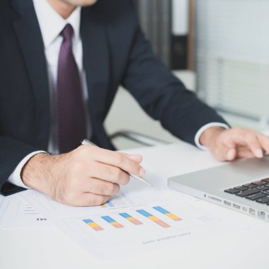 Dizüstü bilgisayar ve belgeleri masada çalışma iş adamı