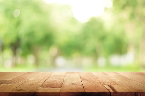 Houten tafelblad op groene achtergrond van bomen in het park wazig — Stockfoto