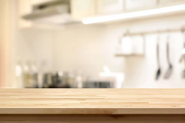 Wood table top (as kitchen island) on blur kitchen interior background