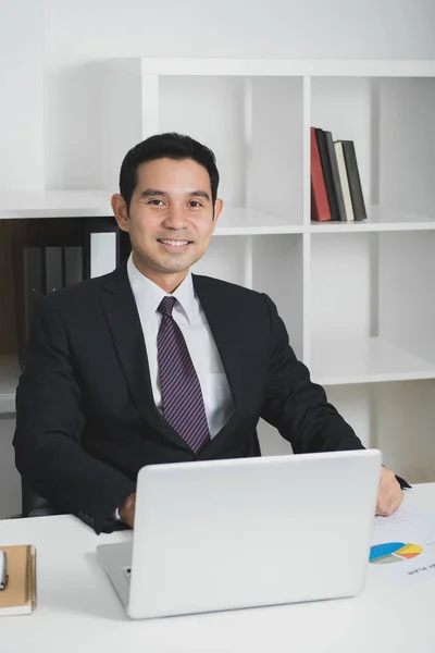 Vacker asiatisk affärsman på jobbet med bärbar dator på bordet — Stockfoto