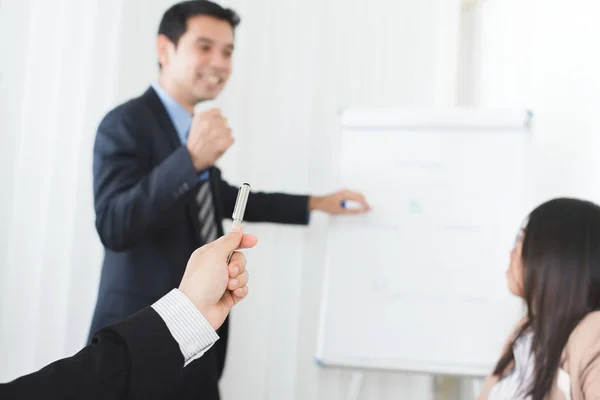 Рука бізнесмена тримає ручку і вказує на потужного лідера зустрічі — стокове фото