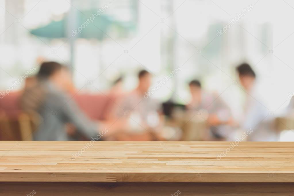 Wood table top on blur background of people in coffee shop 