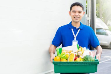 Arabanın yanında gıda sepeti taşıyan Asya teslimatçı