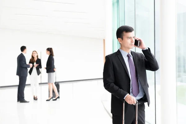 Traveling businessman calling on smartphone at building hallway — Stock Photo, Image