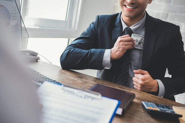 Businessman keeping money into his suit pocket while making agreement