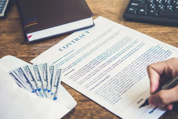 Een man die ondertekening zakelijk contract met geld op de tafel — Stockfoto