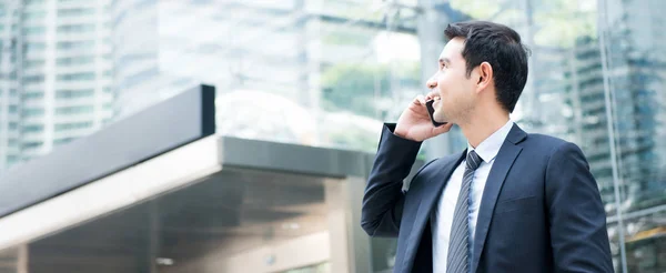 Asian businessman calling on smartphone in front of office build