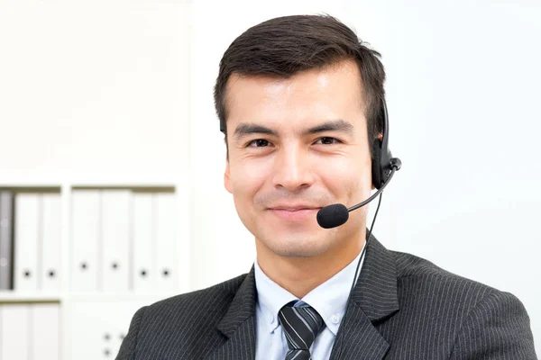 Bonito empresário sorrindo usando fone de ouvido microfone como operador — Fotografia de Stock