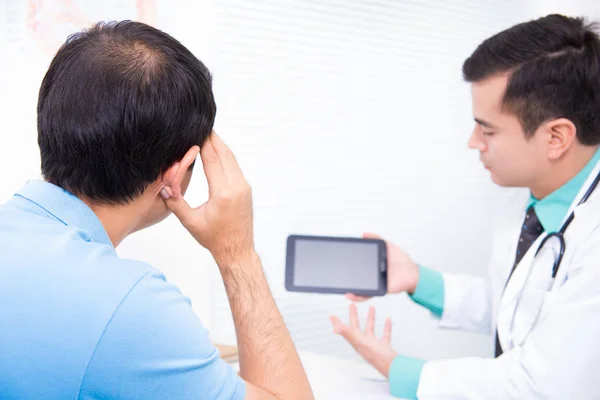 Middle aged man consulting doctor about hair loss problem