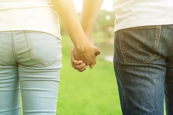 Mladý pár se drží za ruce v parku — Stock fotografie