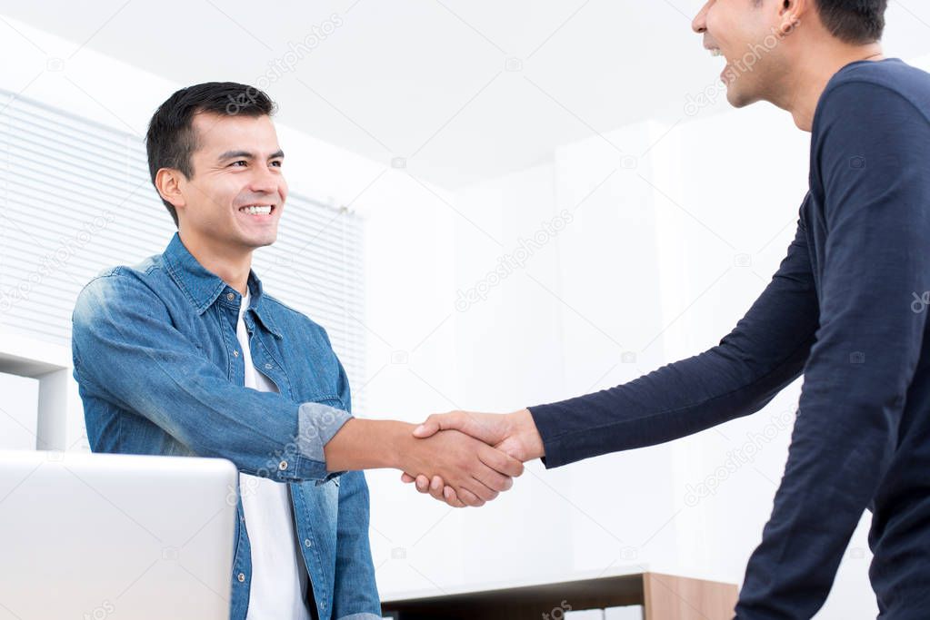 Smiling casual businessmen making handshake in the office