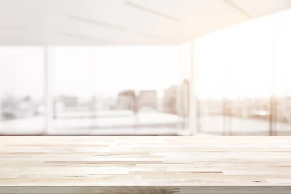 Houten tafelblad in blur lege witte kantoorruimte met glazen wand en stad bouwen weergave in achtergrond — Stockfoto