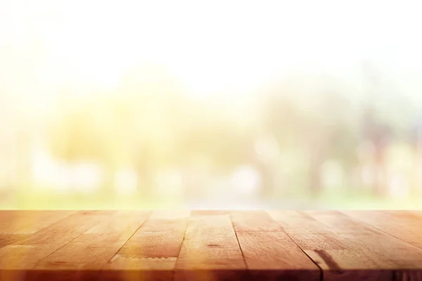 Mesa de madera sobre fondo verde borroso de árboles en el parque —  Fotos de Stock