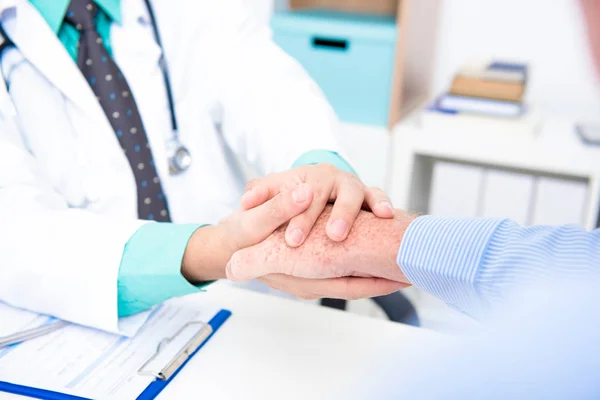 Doctor holding senior male patient hand — Stock Photo, Image