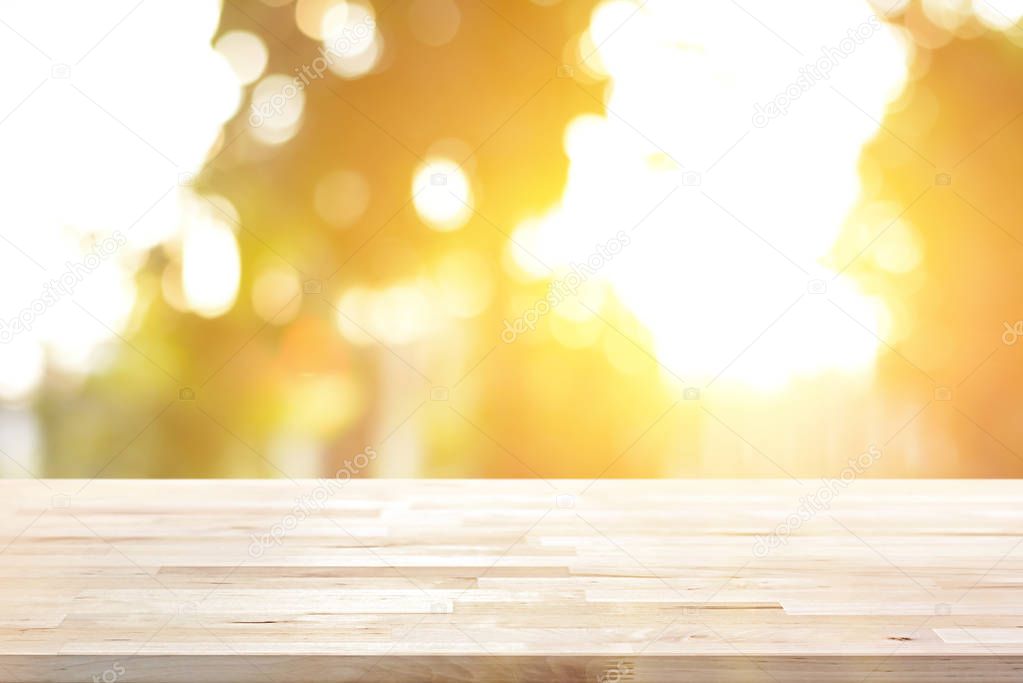 Wood table top on blur bokeh background of sunlight shining through the trees