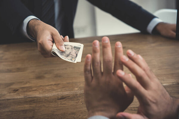 A man declining money, Japanese yen, from a busisnessman 