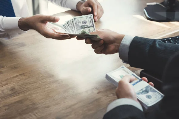 Empresário dando dinheiro ao parceiro na mesa de trabalho — Fotografia de Stock