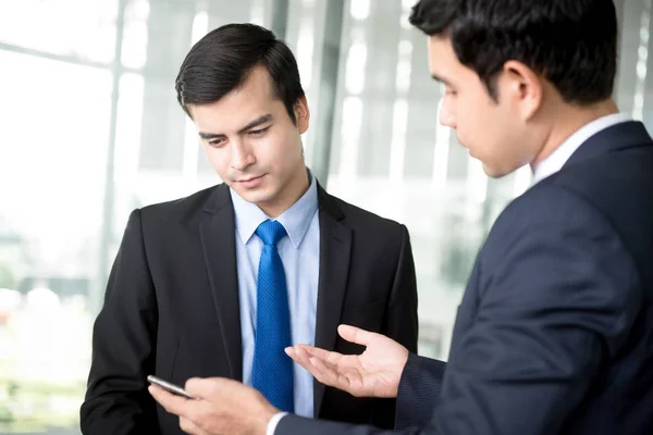 Twee zakenlieden smartphone kijken en bespreken — Stockfoto
