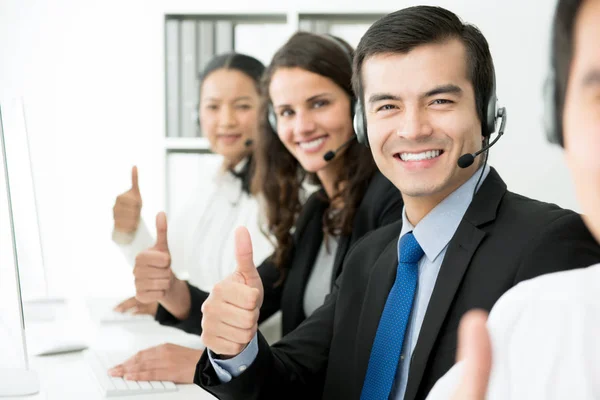 Sonriente equipo de atención al cliente dando pulgares hacia arriba — Foto de Stock