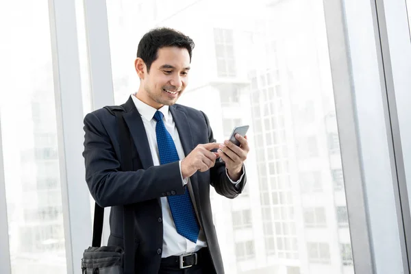 Aziatische zakenman met behulp van mobiele telefoon tijdens het wandelen in het gebouw van hal — Stockfoto