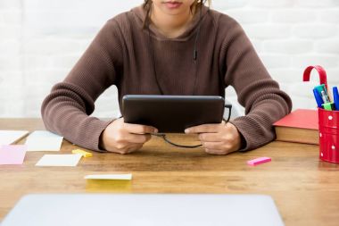 Kolej kız öğrenci masada tablet bilgisayar kullanarak