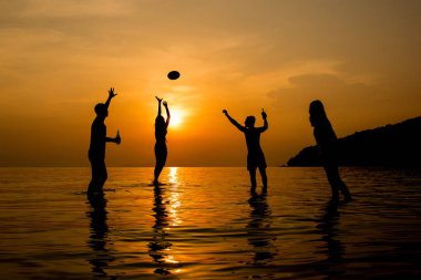 Plajda yaz günbatımı - silhoue oynayan arkadaş grubu
