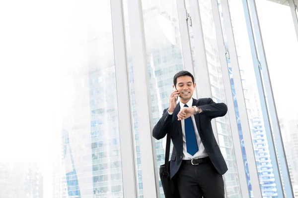 Businessman watching the time and calling on cell phone while wa — Stock Photo, Image