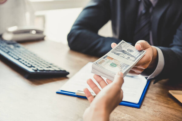 Businessman giving money to his partner while making contract