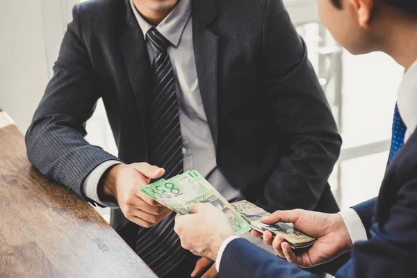 Empresário dando dinheiro, notas de dólar australiano, a sua parte — Fotografia de Stock