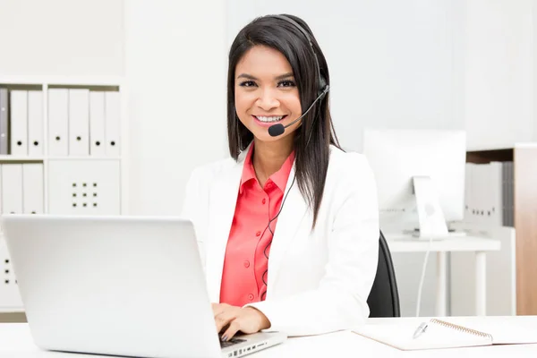 Businesswoman wearing microphone headset using laptop computer i — Stock Photo, Image
