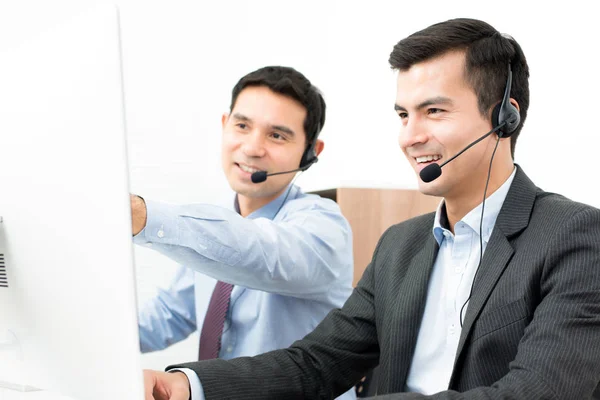 Empresarios con auriculares y mirando la pantalla de la computadora —  Fotos de Stock