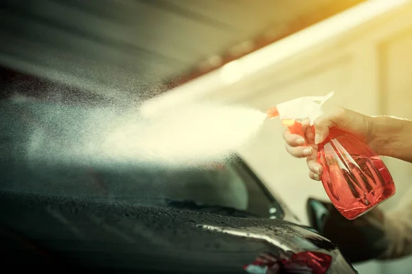 Hand holding spray bottle spraying car, about to clean — Stock Photo, Image