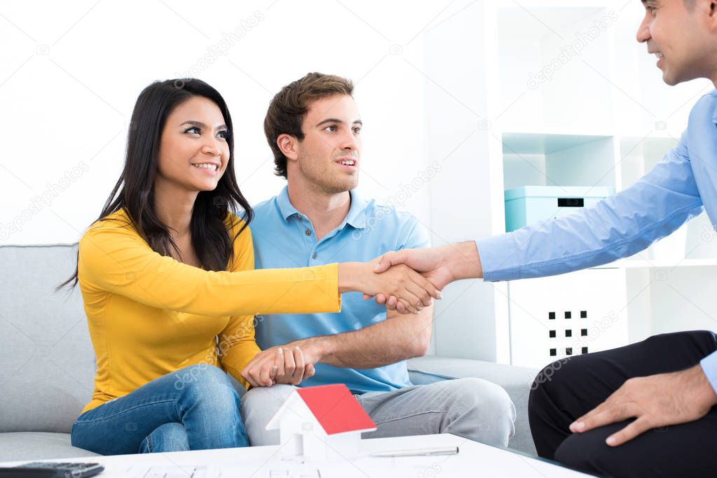 Young couple meeting with real estate agent at home
