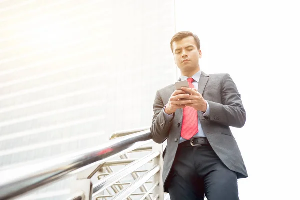 Zakenman met behulp van de smartphone tijdens het wandelen op wandelpad brug in — Stockfoto