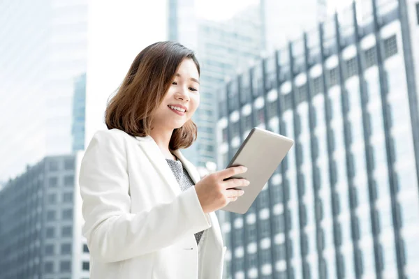 Asiática mujer de negocios utilizando tableta ordenador al aire libre en desenfoque offic —  Fotos de Stock