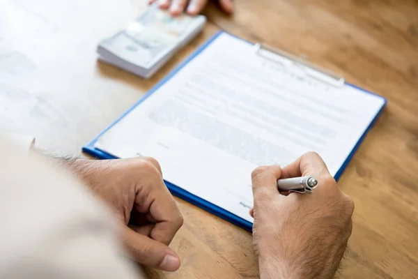 Een man ondertekening contract en het krijgen van geld — Stockfoto