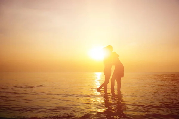 Silhouette eines romantischen Paares, das sich bei Sonnenuntergang am Strand umarmt — Stockfoto