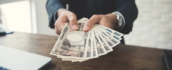 Businessman giving money, Japanese yen banknotes - panoramic ban