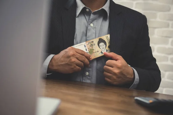 Empresario poniendo dinero, billetes coreanos ganados, en su traje — Foto de Stock