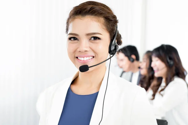 Mulher sorrindo usando fone de ouvido microfone no call center — Fotografia de Stock