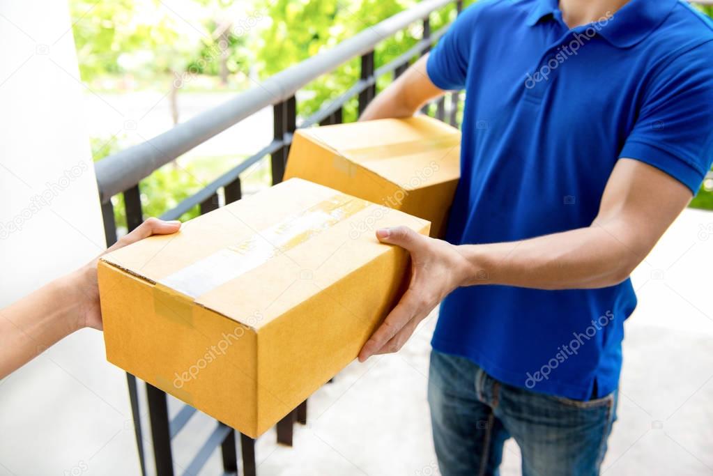 Delivery man in blue uniform handing parcel box to recipient